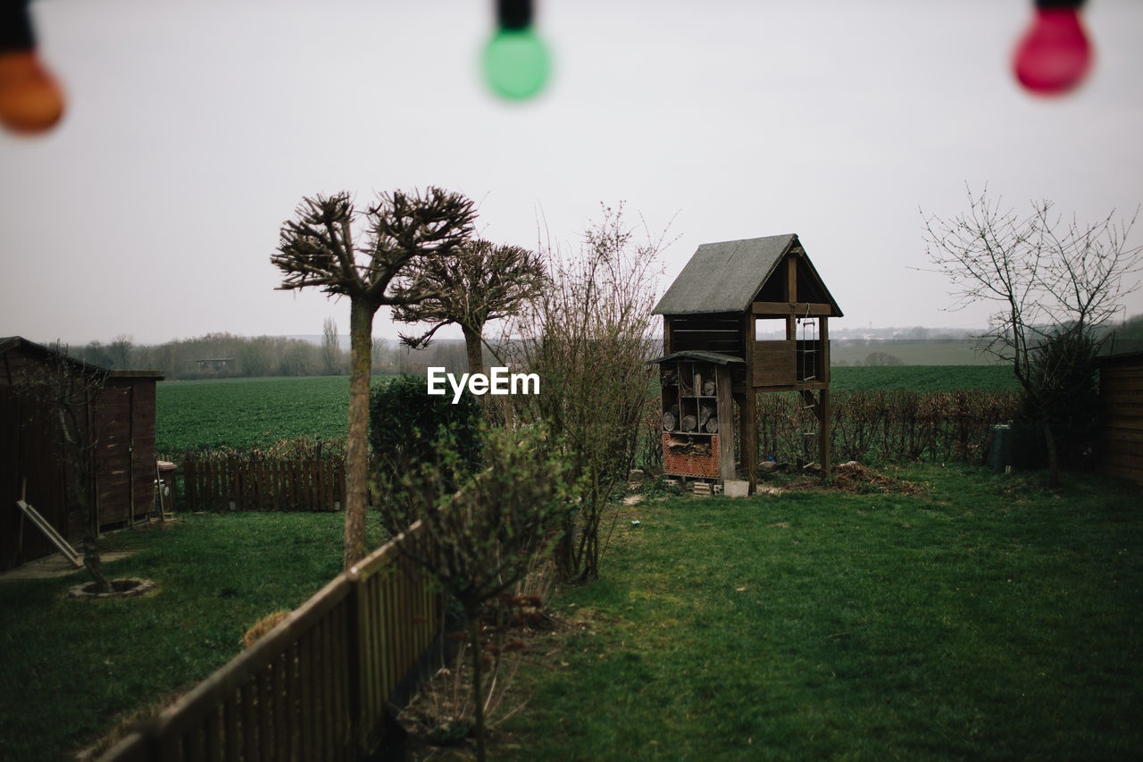 House on field by trees against sky