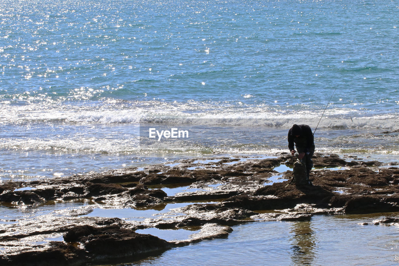 REAR VIEW OF WOMAN LOOKING AT SEA