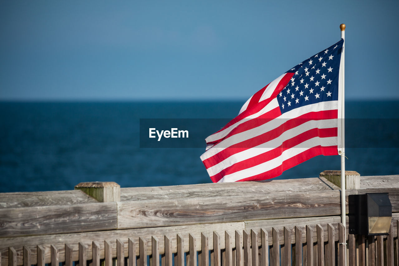 Flag by sea against blue sky