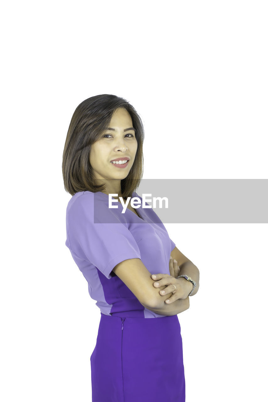 PORTRAIT OF SMILING YOUNG WOMAN AGAINST WHITE BACKGROUND