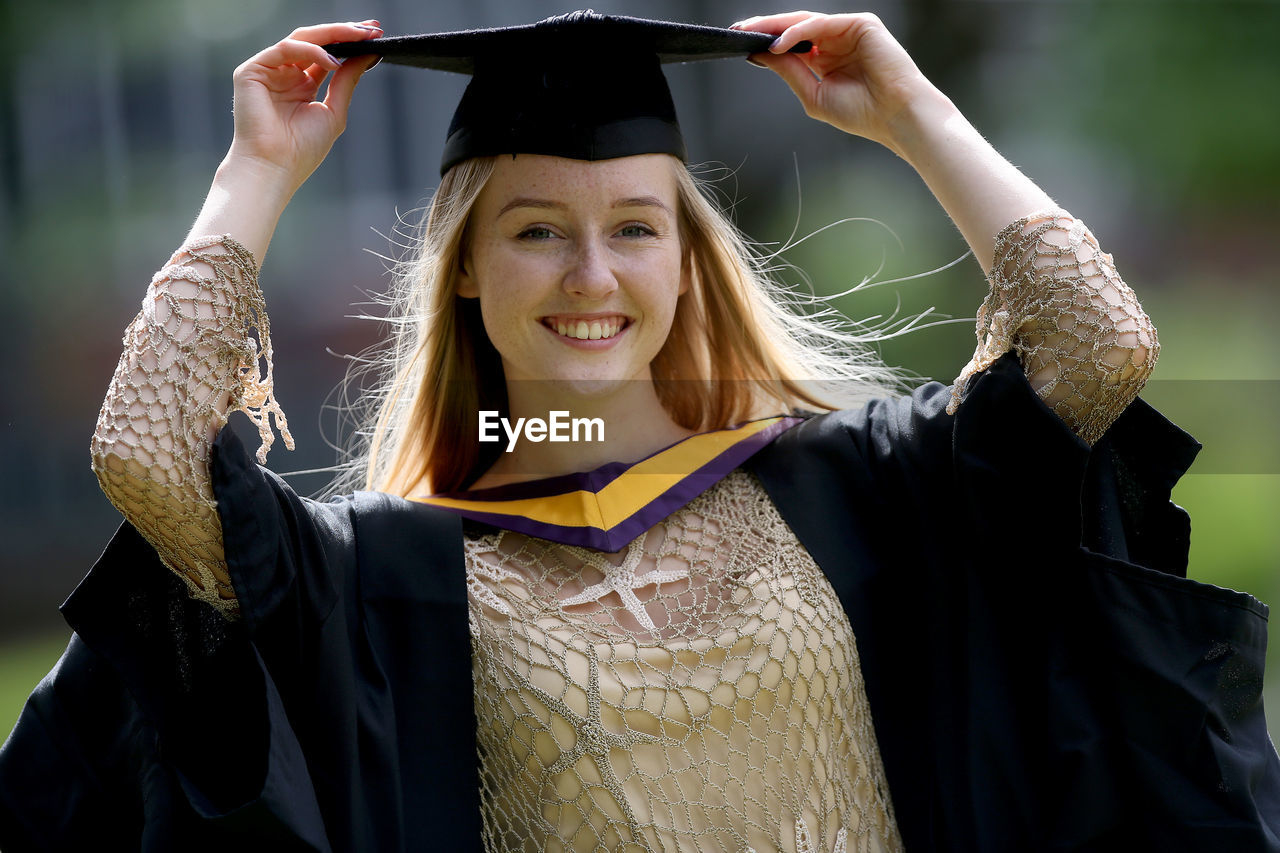 PORTRAIT OF A SMILING YOUNG WOMAN WITH ARMS OUTSTRETCHED