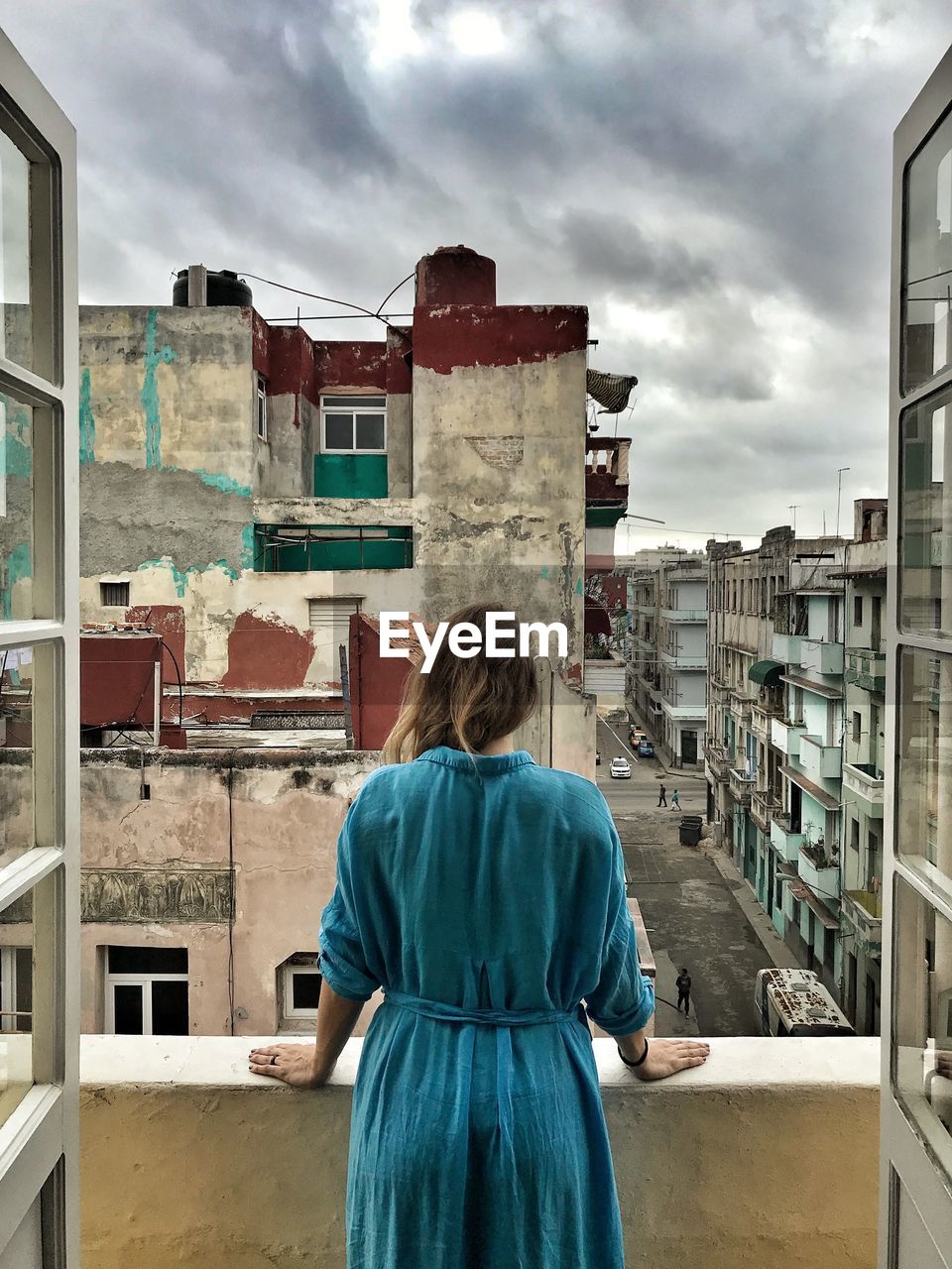 Rear view of mid adult woman standing in balcony against cloudy sky