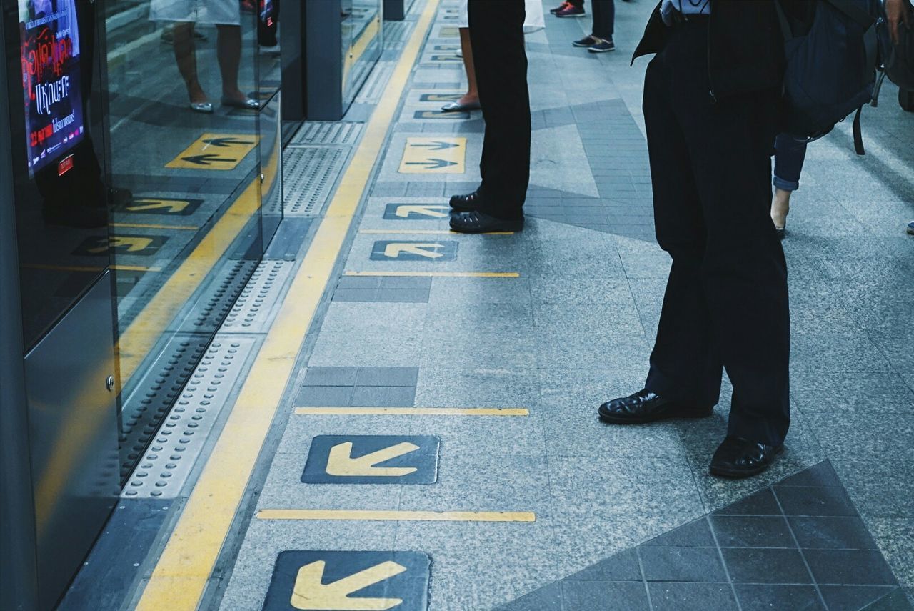 Low section of people standing at railroad station platform