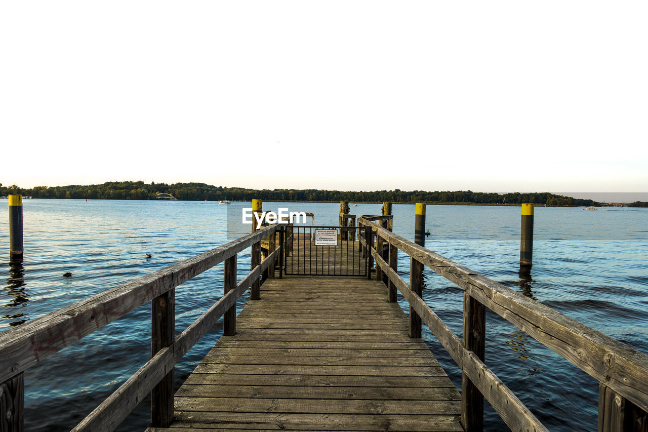 Pier over calm sea against clear sky