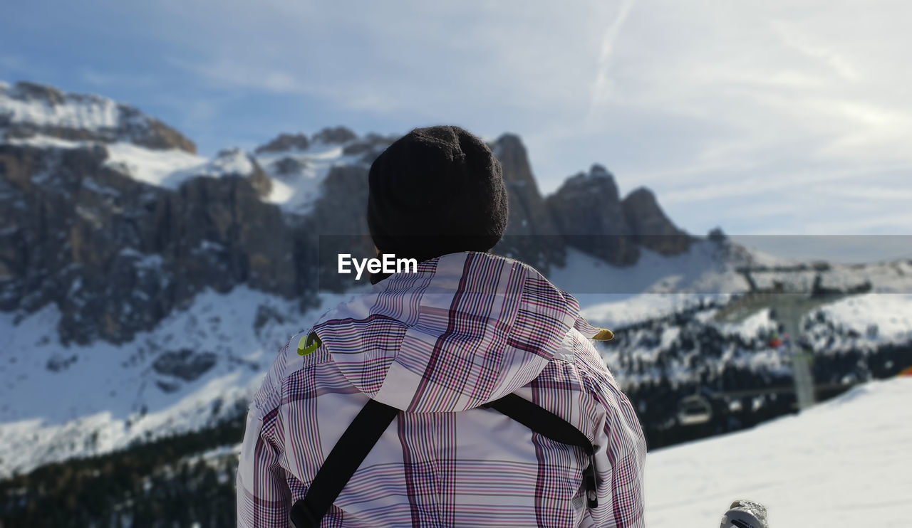 Rear view of woman standing on snowcapped mountain