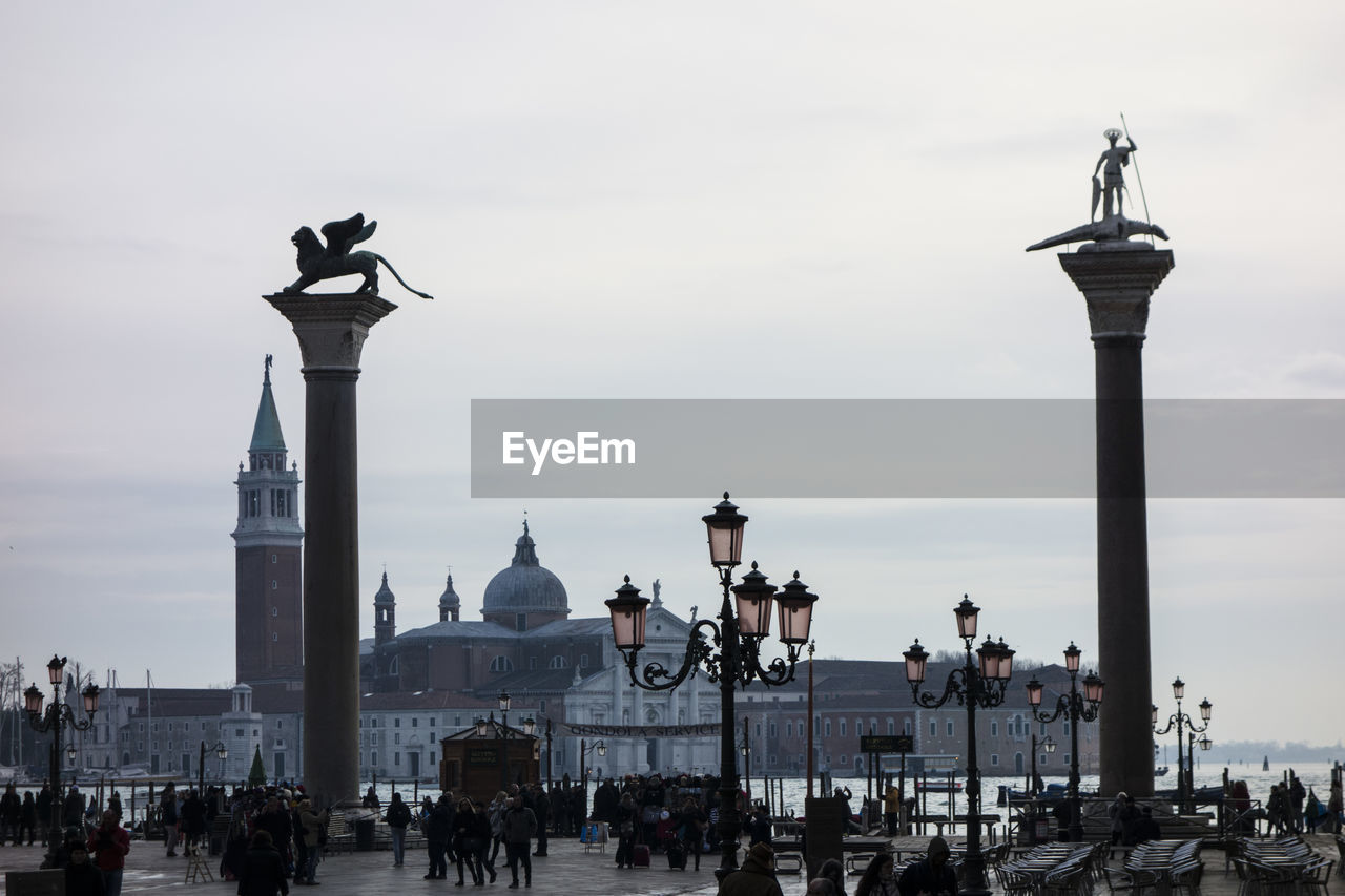 People at piazza san marco with san giorgio maggiore against sky
