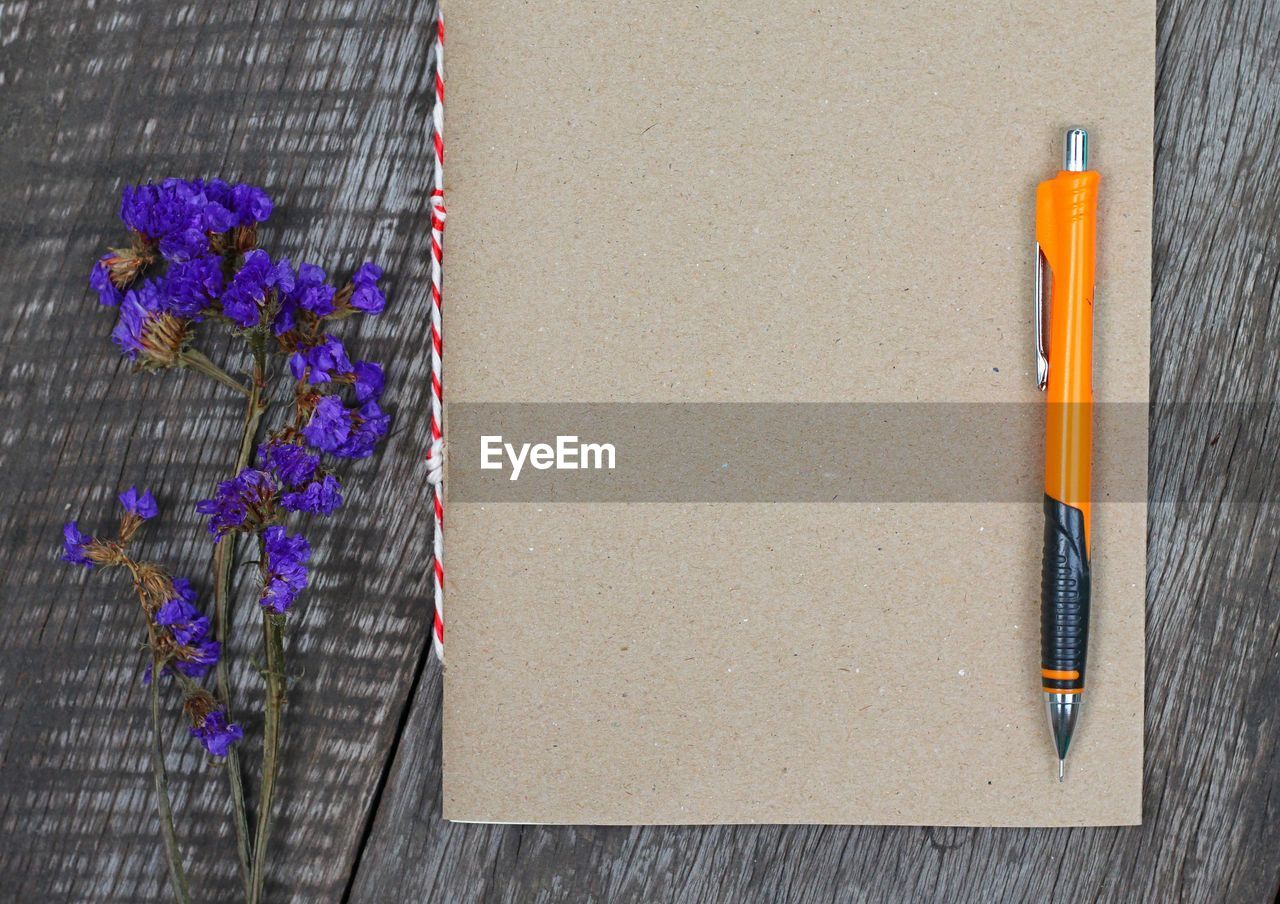 Directly above view of flowers and diary with pen on table