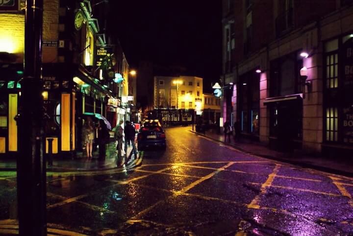 VIEW OF ILLUMINATED CITY STREET AT NIGHT