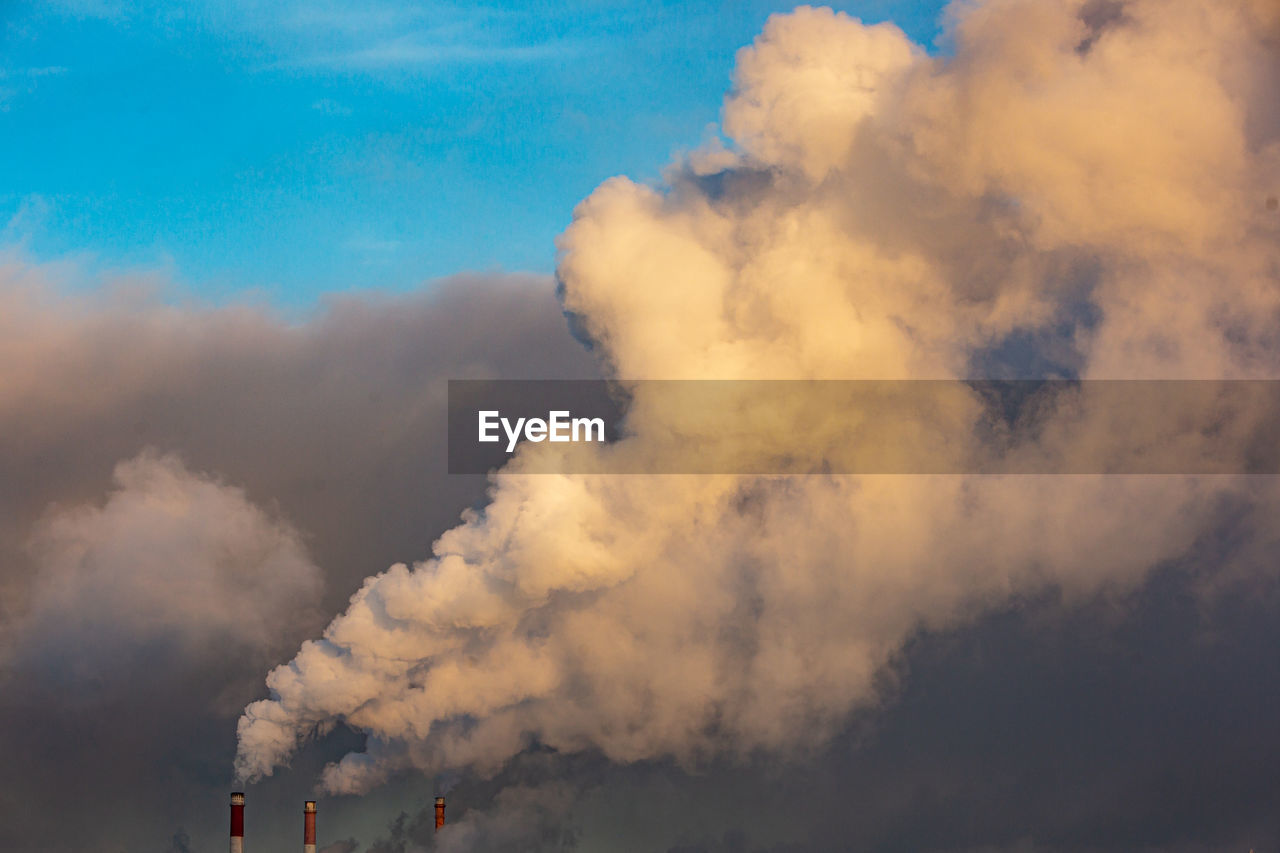 Low angle view of smoke emitting from factory against sky