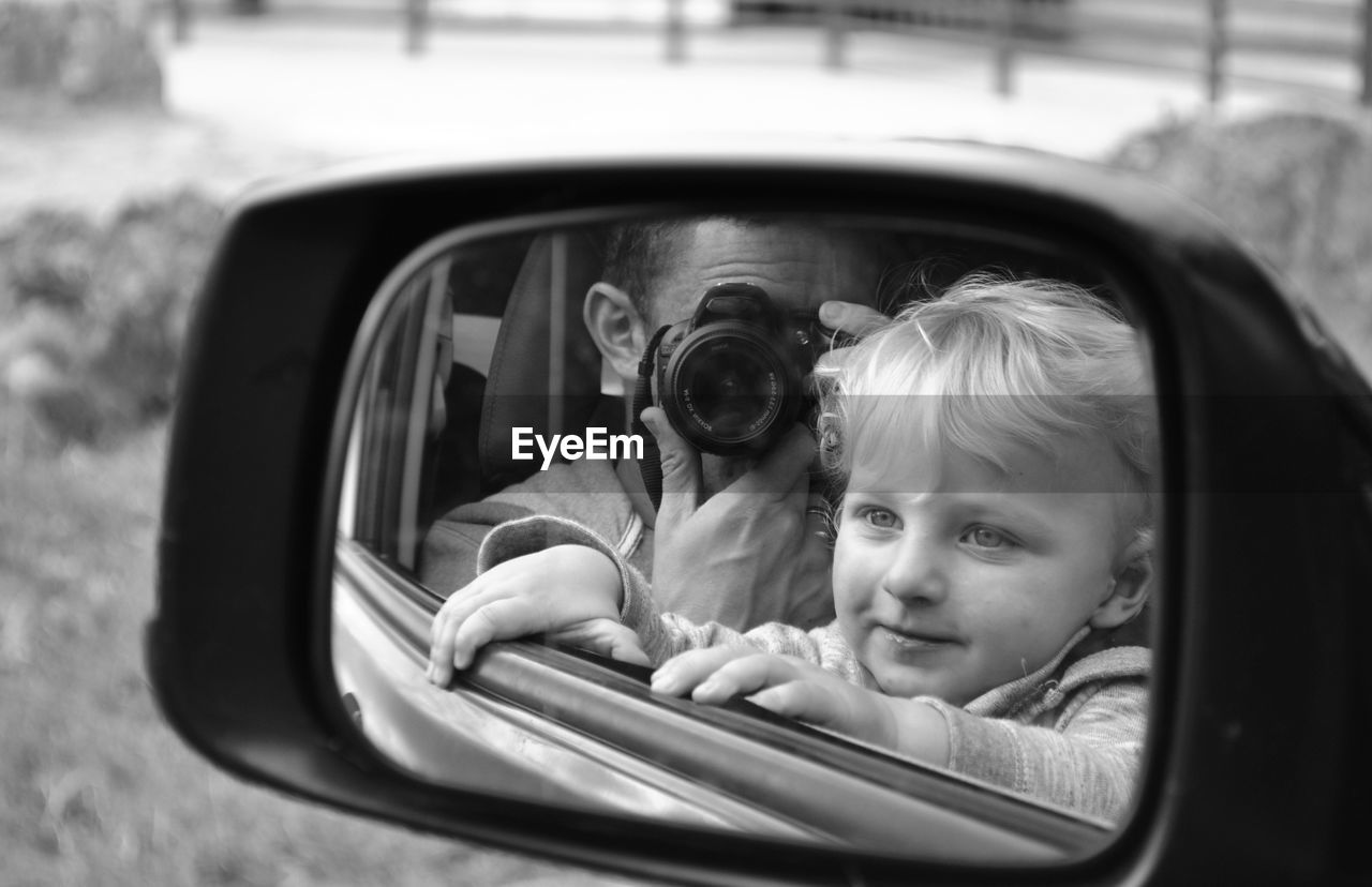 PORTRAIT OF CUTE BOY WITH CAR IN MIRROR