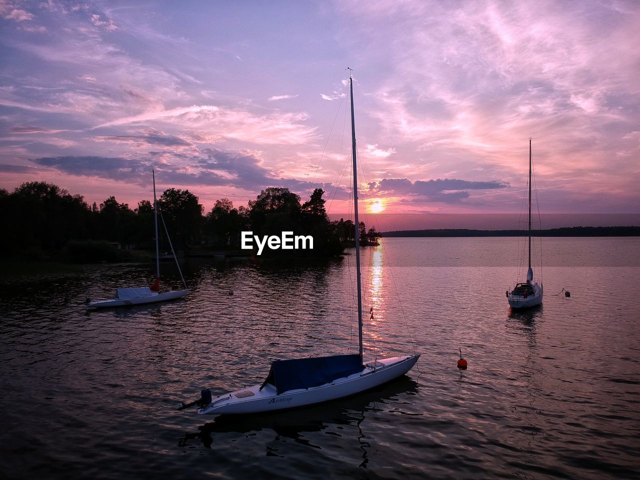 BOATS MOORED IN LAKE AGAINST SKY DURING SUNSET