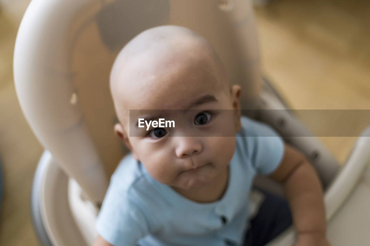 Portrait of cute baby sitting in high chair at home