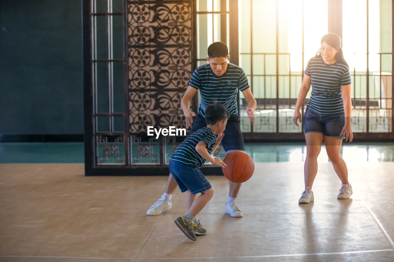 Parents playing basketball with son in court