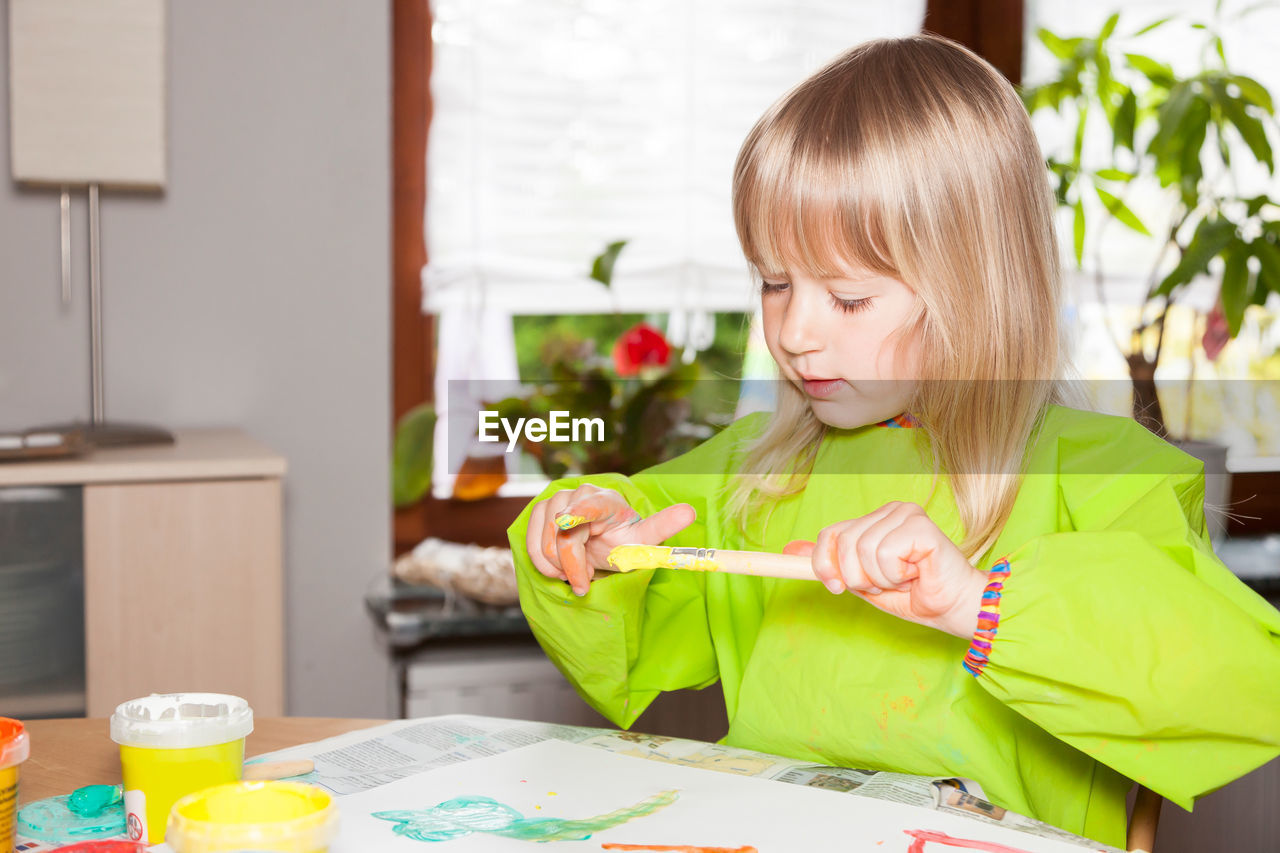 Girl painting on paper while sitting at home