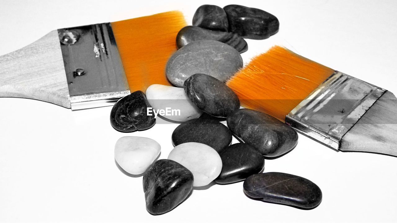 Close-up of paintbrushes and stones on white background