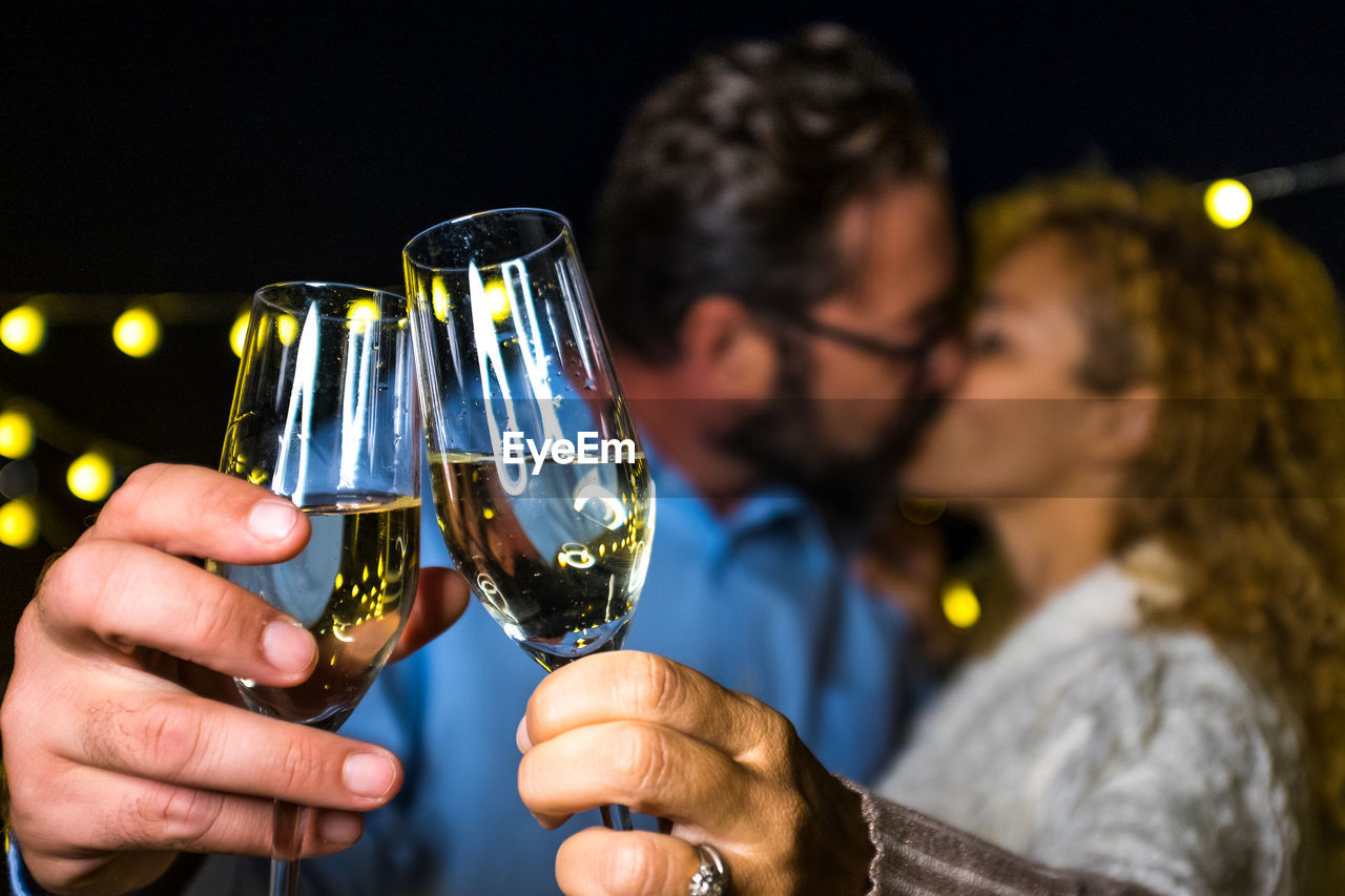 Couple kissing while holding champagne outdoors