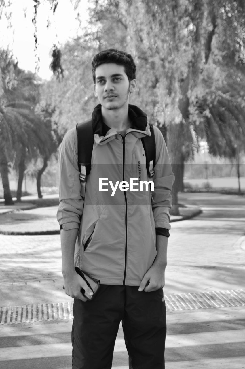 YOUNG MAN STANDING ON TREE