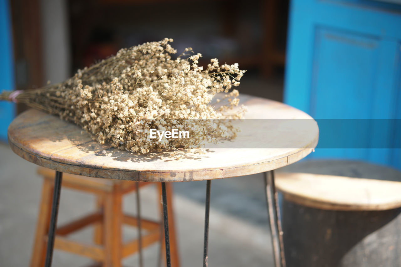 Dried flower bouquet on wooden chair near blue door