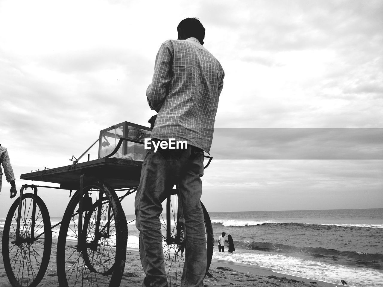 Rear view of vendor selling at beach against cloudy sky