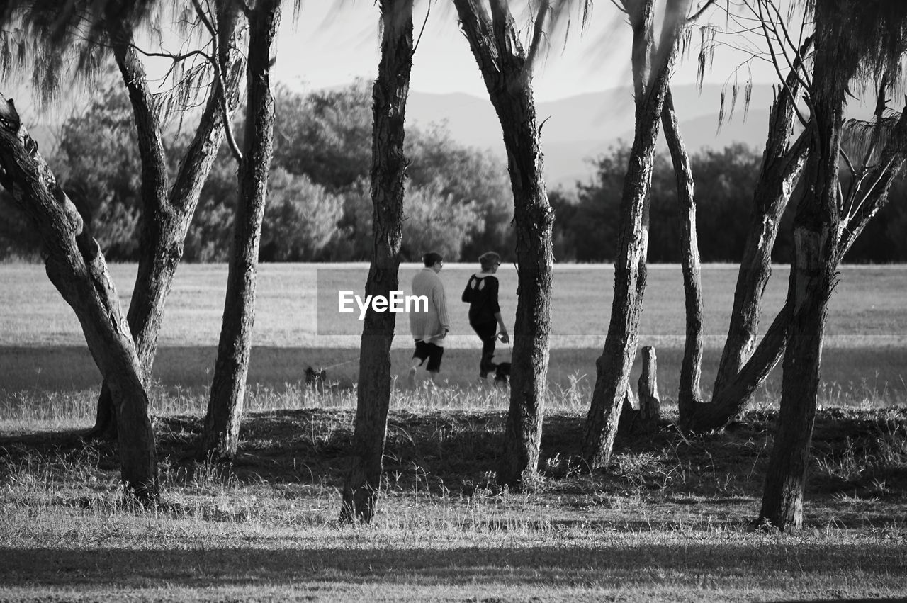 Women walking on grassy field by trees