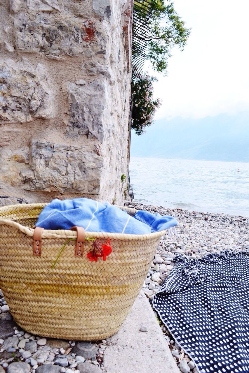 Clothes in wicker basket and rocky shore