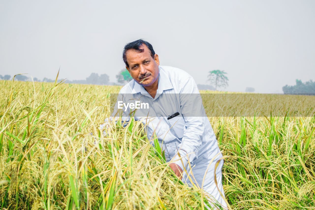 Portrait of man standing on field against sky