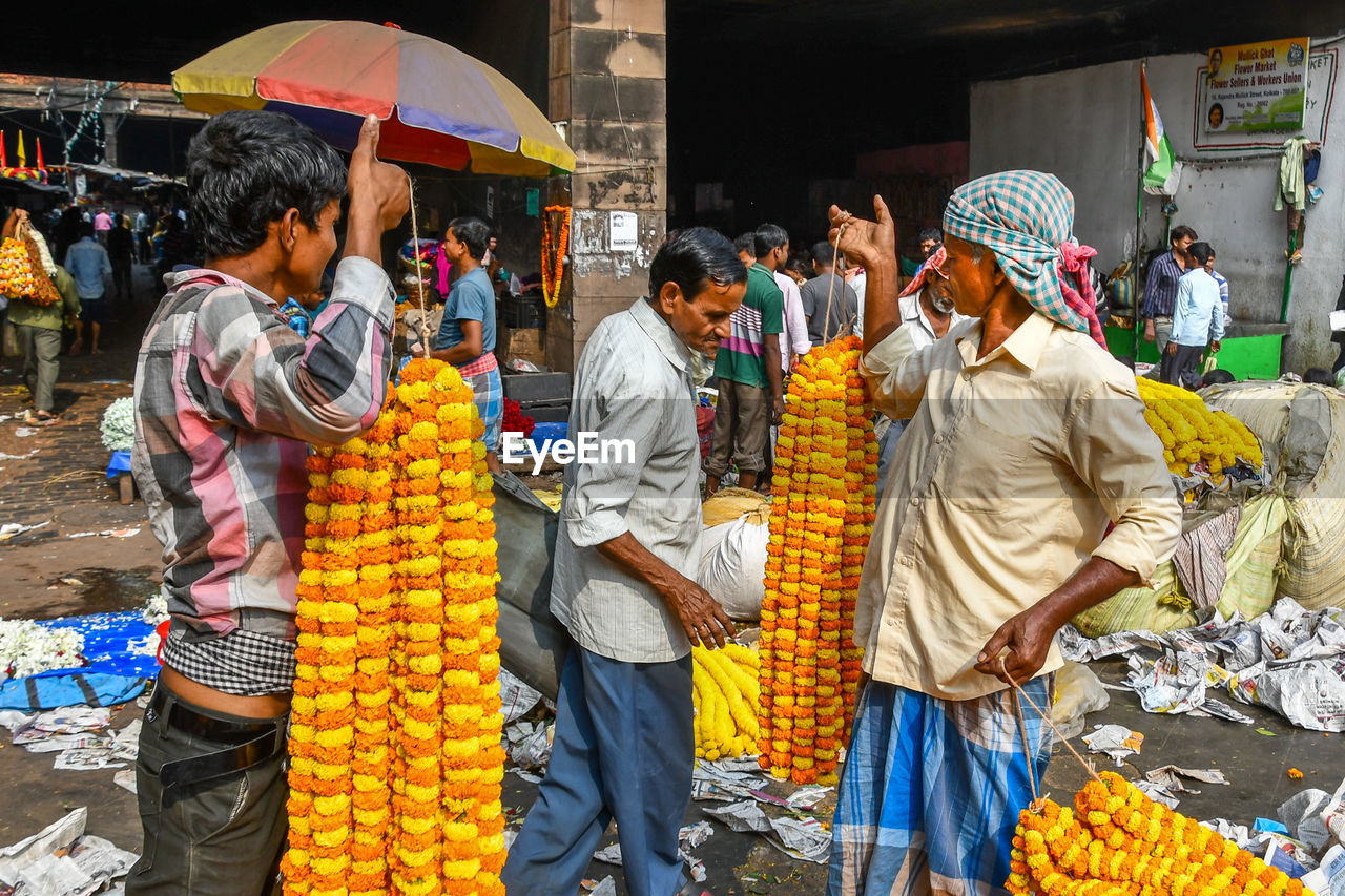 GROUP OF PEOPLE STANDING AT MARKET STALL