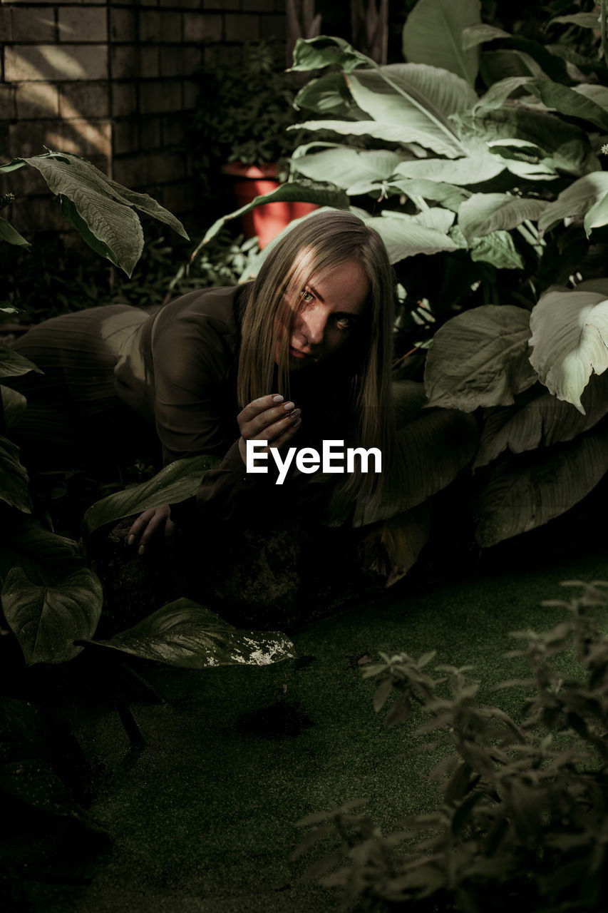 Portrait of young woman sitting by plants