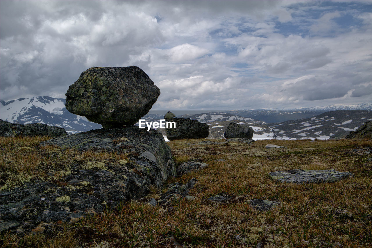 Rocks on field against cloudy sky