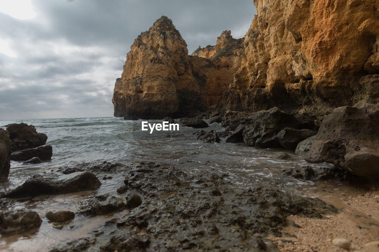 Rock formations on sea shore against sky