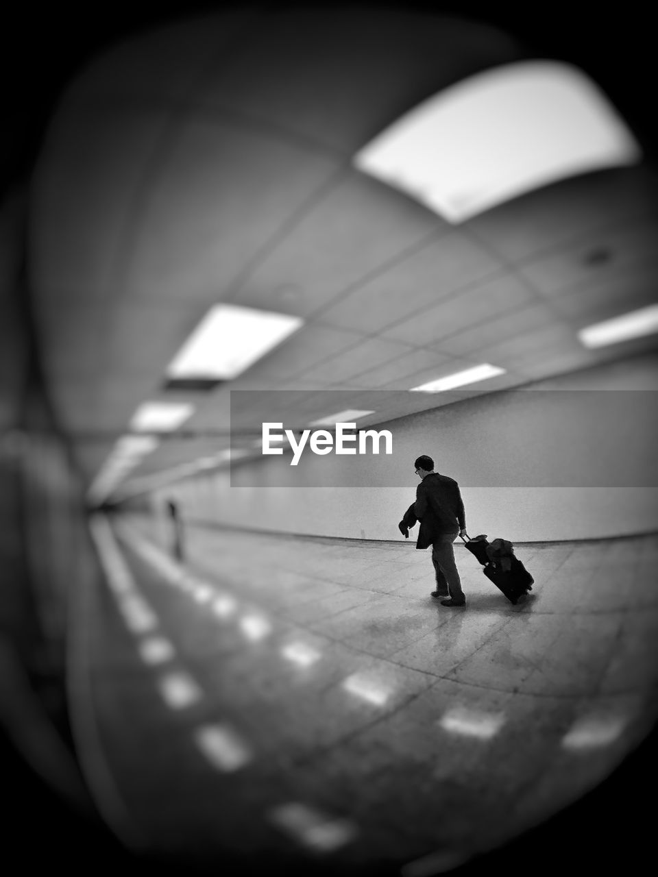 Fish-eye view of man pulling luggage at airport