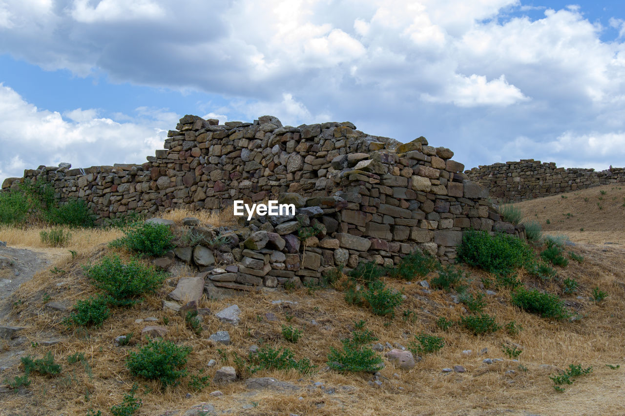 STACK OF STONES ON FIELD AGAINST SKY