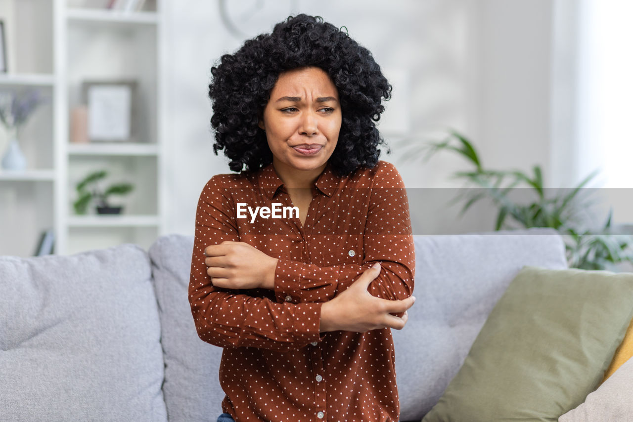 portrait of young woman using mobile phone while lying on bed at home