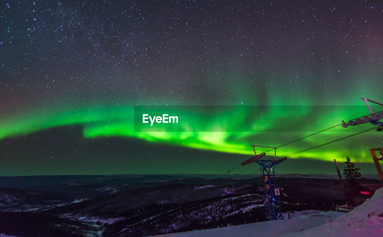 Scenic view of illuminated snowcapped mountains against sky at night