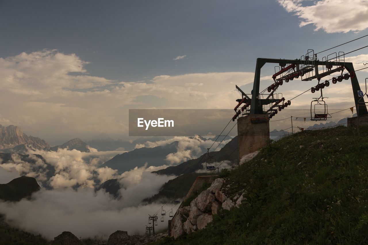 Low angle view of ski lift on mountain against sky in foggy weather during sunset