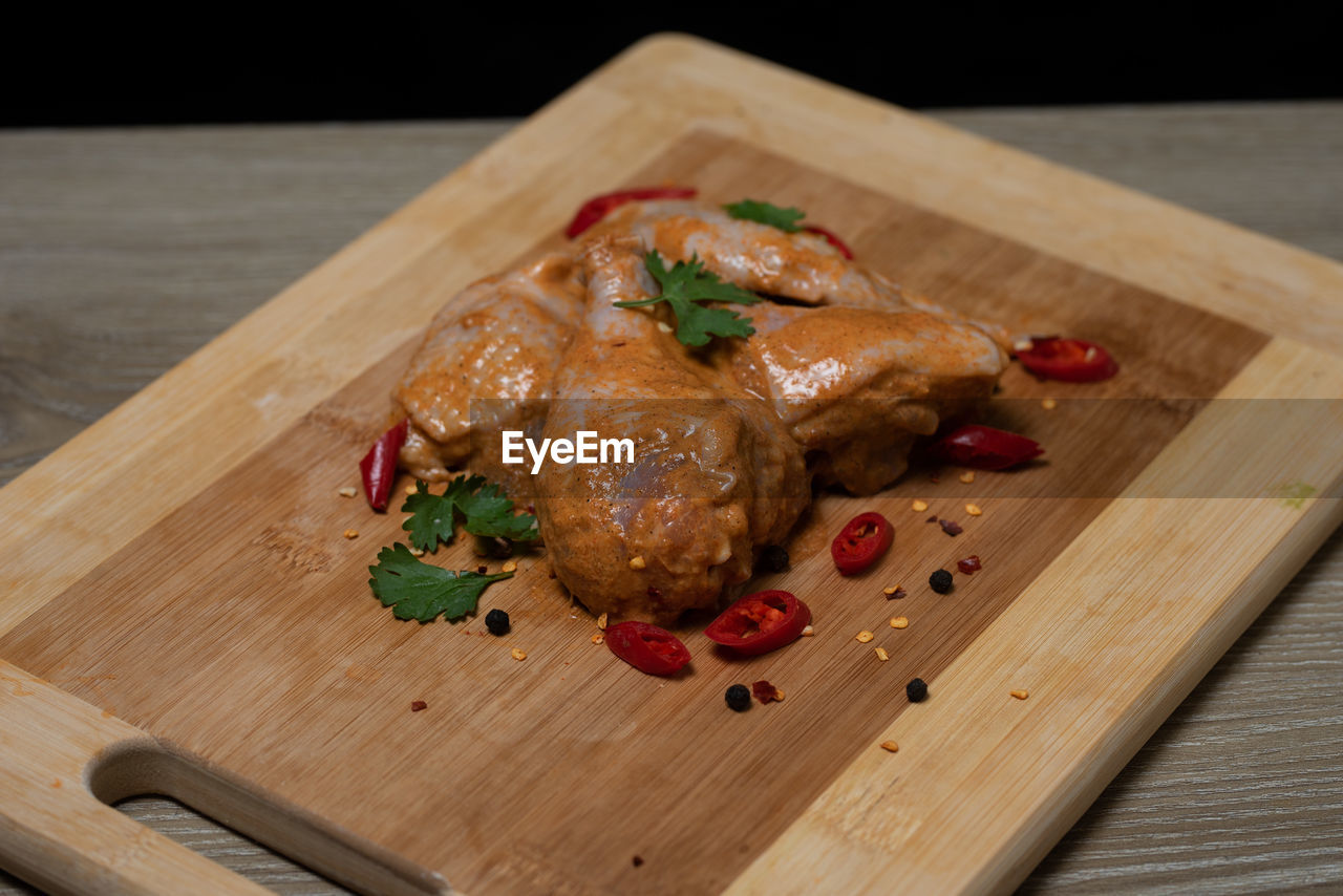 HIGH ANGLE VIEW OF MEAT IN CONTAINER ON CUTTING BOARD