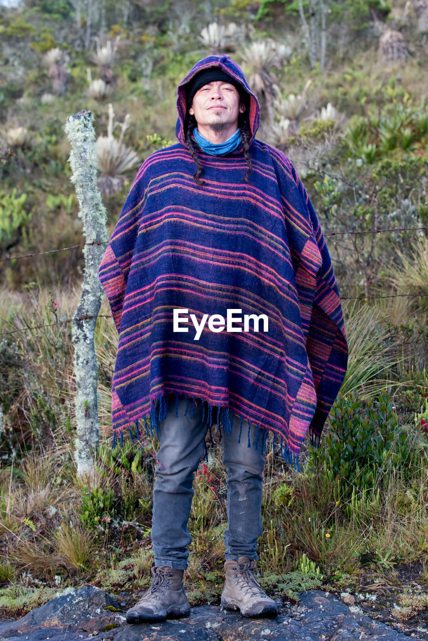 Colombian native american man in traditional clothing standing in forest