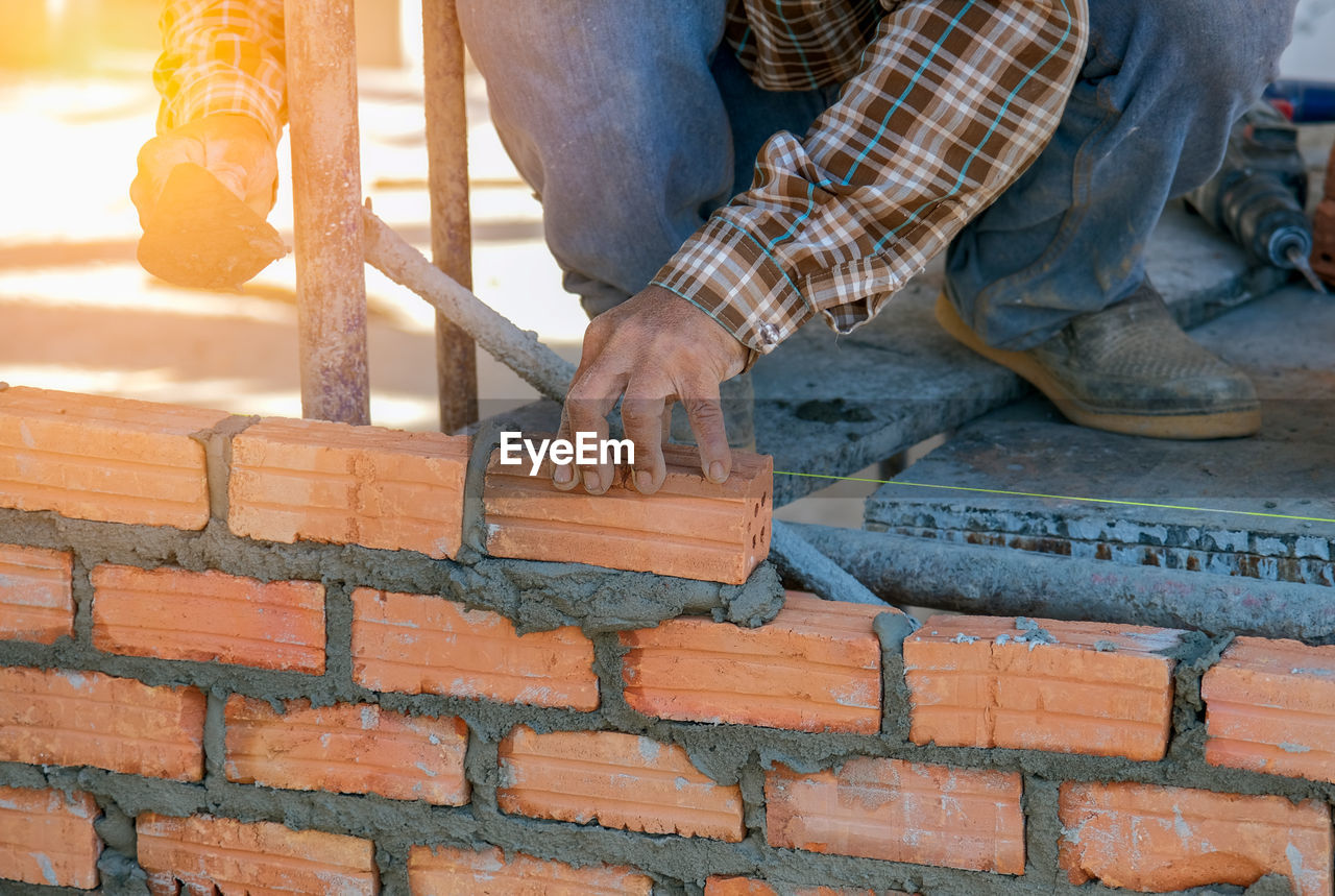 LOW SECTION OF MAN WORKING ON WALL