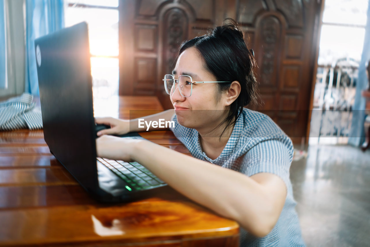 Portrait of woman using laptop while sitting on table