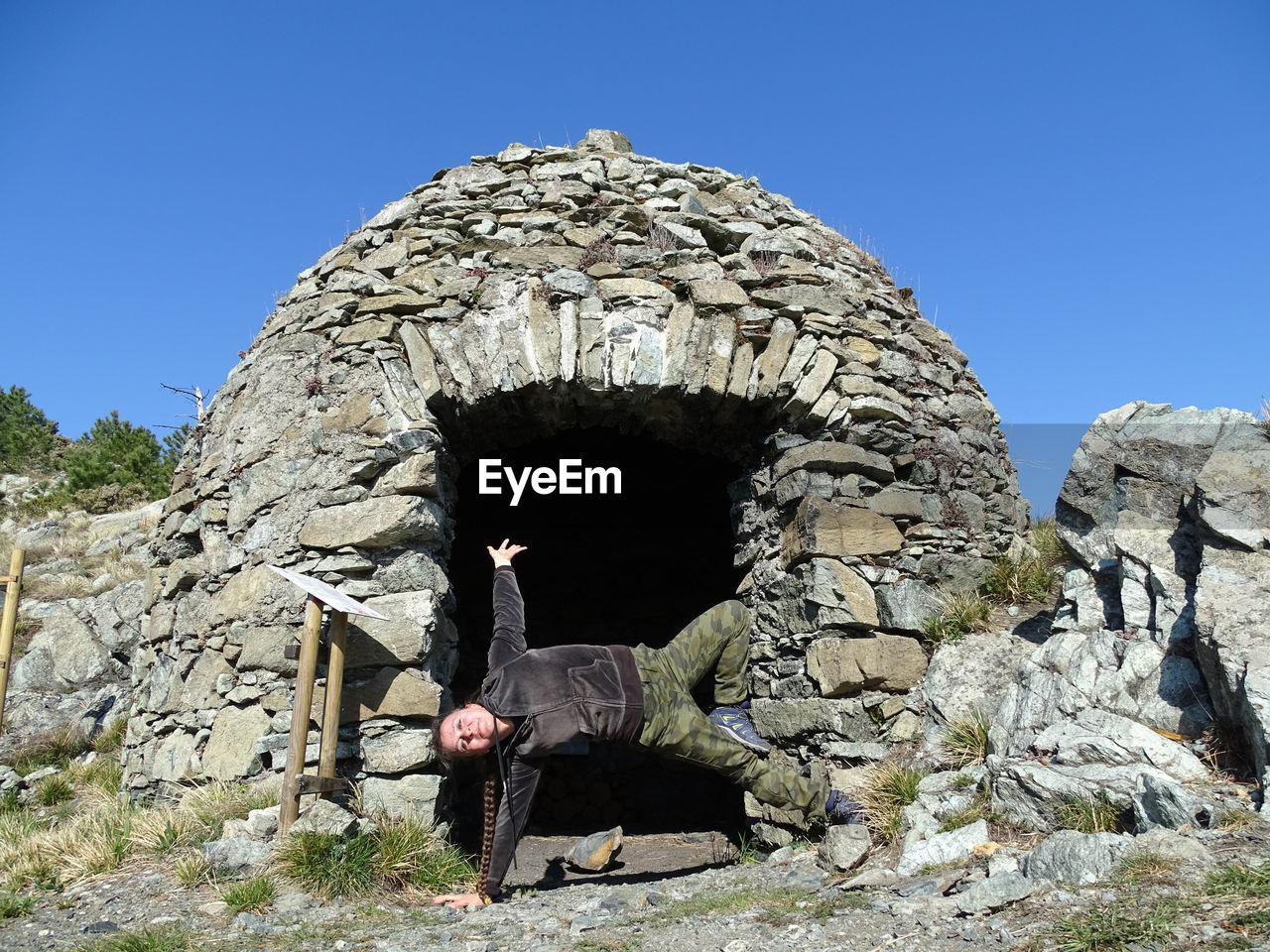 Woman performing stunt at historic building against clear sky