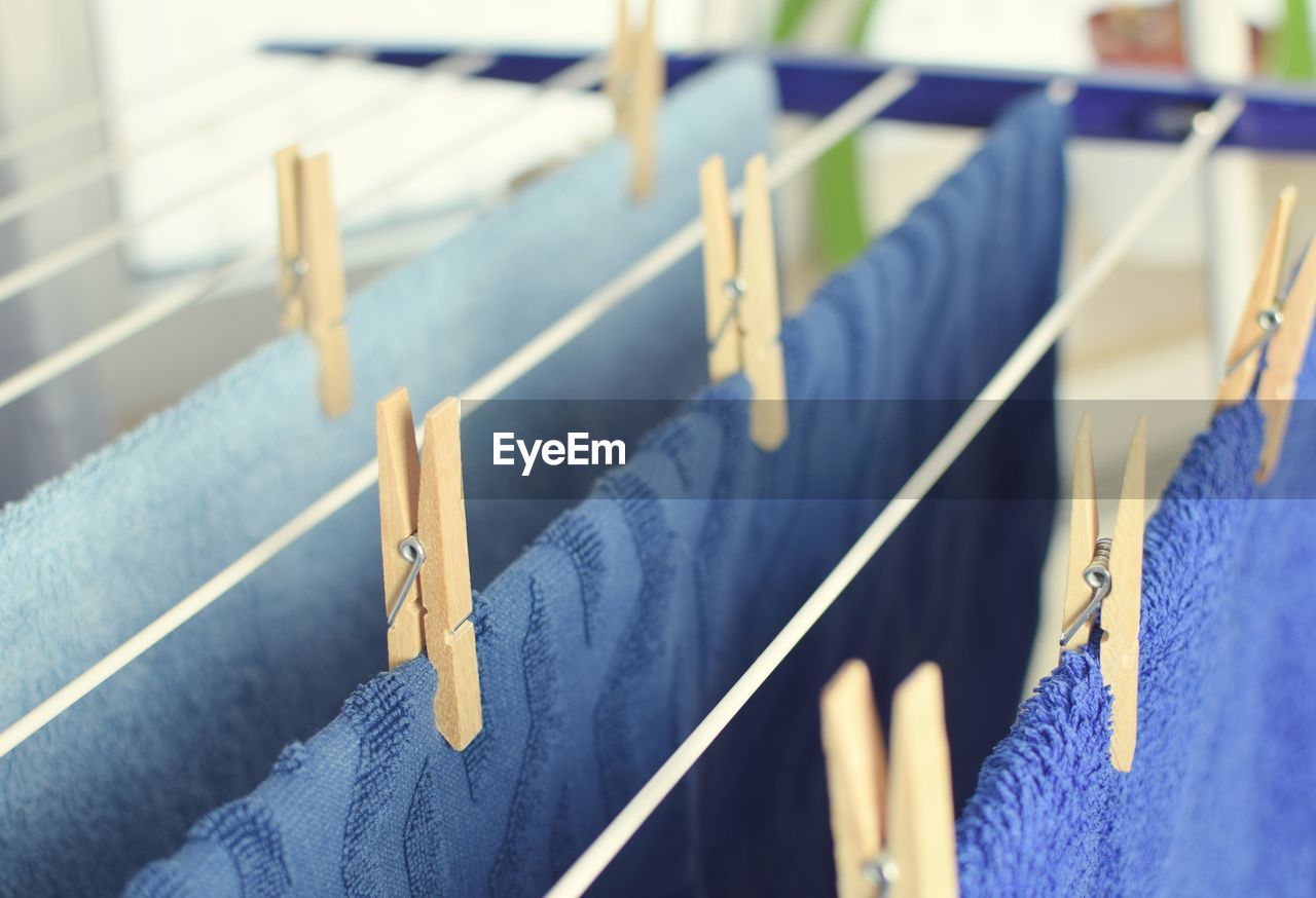 CLOSE-UP OF CLOTHES HANGING ON CLOTHESLINE AGAINST BLUE SKY