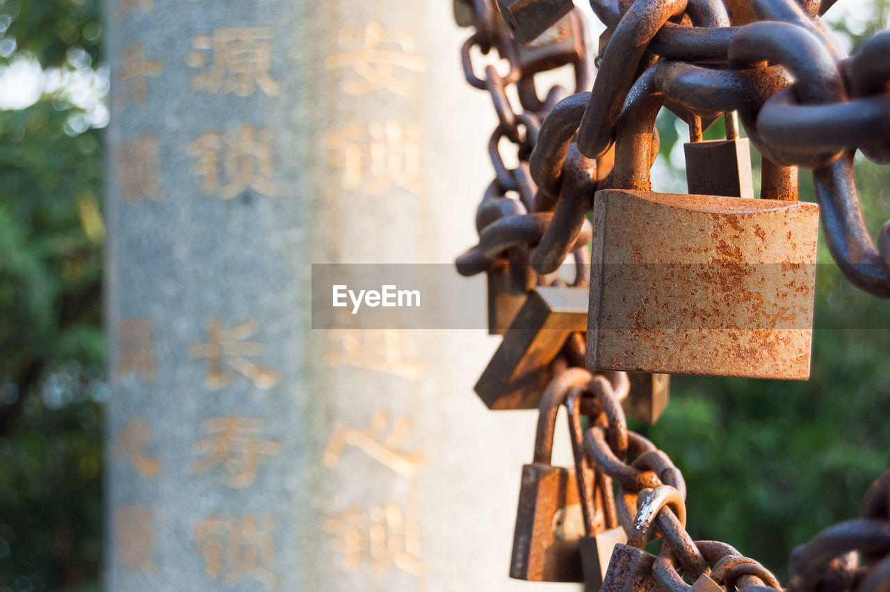 Close-up of rusty padlocks with chain by column