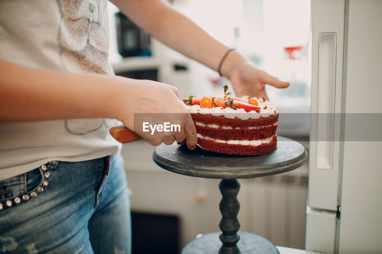 Midsection of woman keeping cake on stand at home