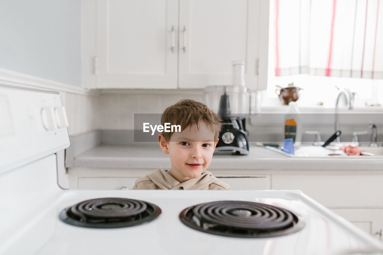 Portrait of boy standing in kitchen at home