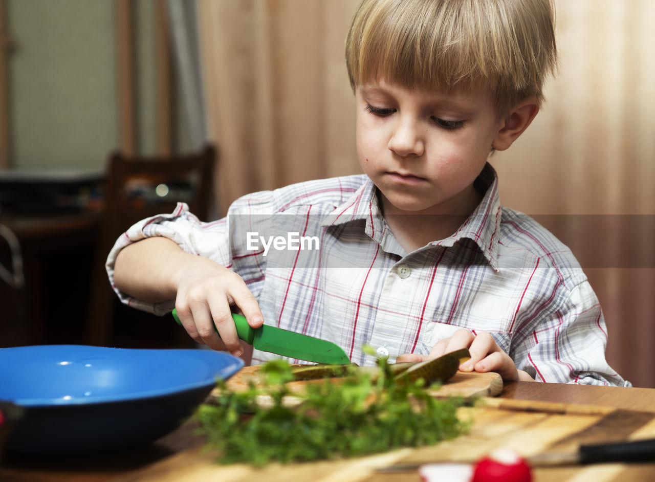 Close-up of boy with vegetables on table