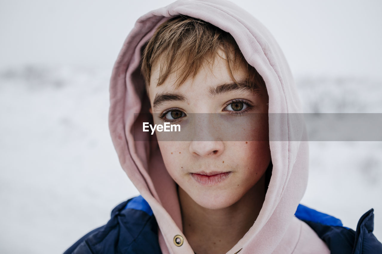 Teenage boy with brown eyes in warm clothing on snow