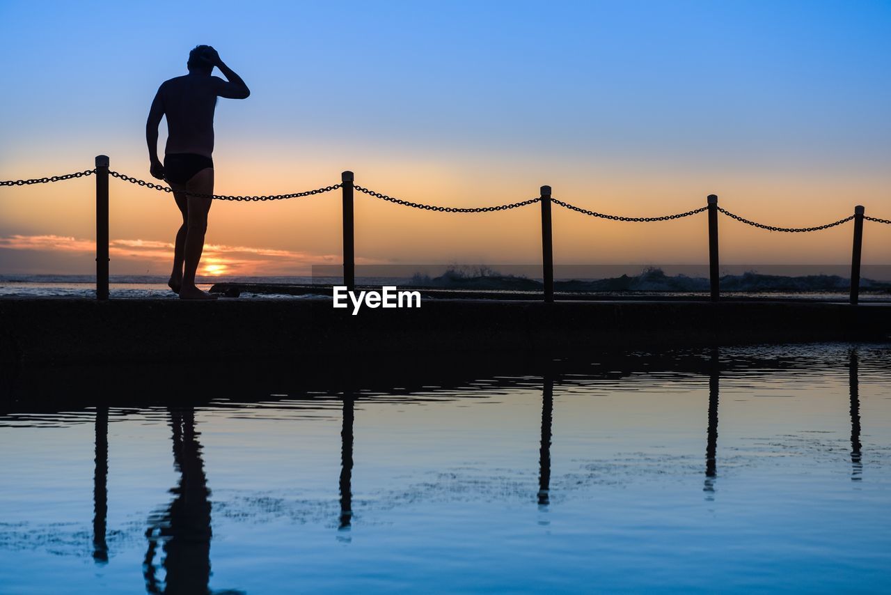 SILHOUETTE MAN STANDING ON BRIDGE AGAINST SKY