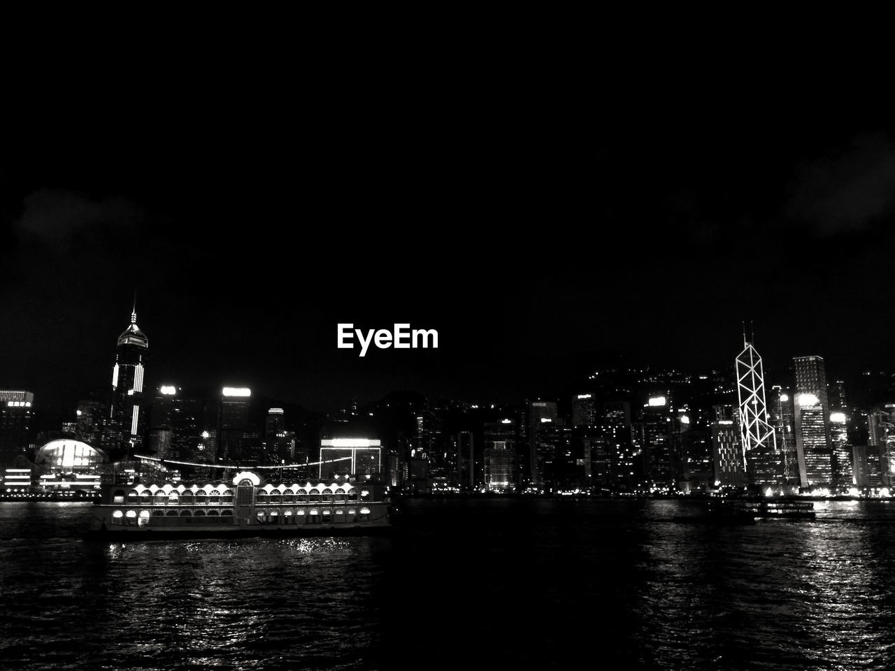 Sea and buildings against clear sky at night