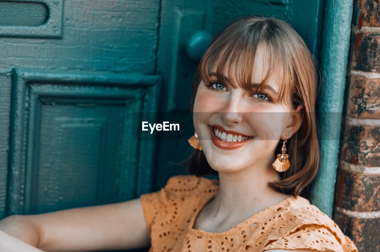 Close-up of smiling woman sitting by door 