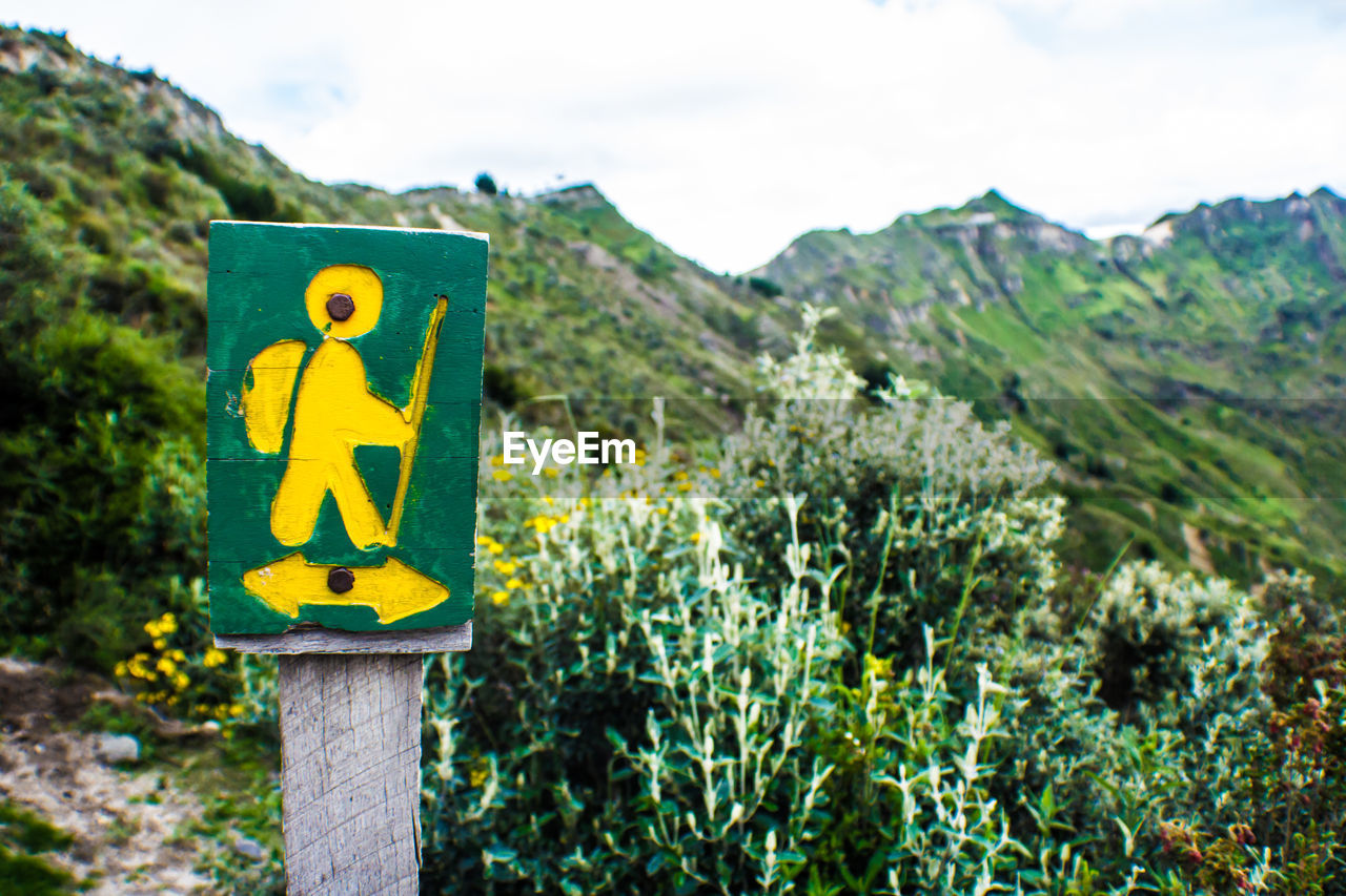 CLOSE-UP OF ROAD SIGN AGAINST MOUNTAINS